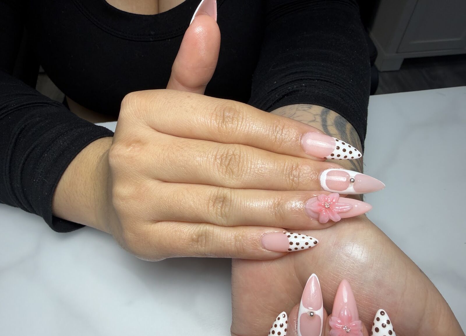 Pink stiletto nails with polka dots, bows and 3D flower charm by a Lone Tree nail artist